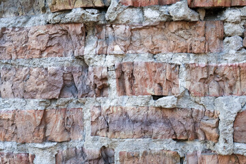 Close-up of a weathered brick wall with cracks and rough textures, showcasing the aged and rustic appearance of old construction materials.