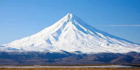 Majestic Snow-Capped Volcano Under Clear Blue Sky in Scenic Landscape