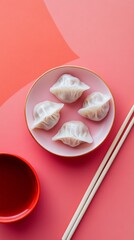 Four Chinese dumplings on a plate with chopsticks and sauce in a bowl next to it. Chinese New Year themed flat lay photo with pastel background and copy space.