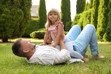 Fototapeta premium Father and his daughter spending time together on green lawn in park
