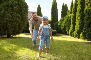 Fototapeta premium Father and his daughter spending time together on green lawn in park