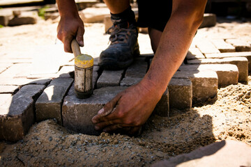 Pflasterer legen Steine und haut mit dem Hammer