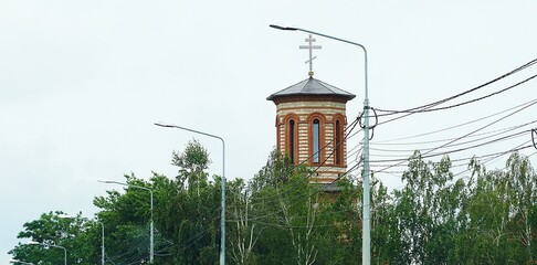 Wieża kościoła prawosławnego i widoczny krzyż na szczycie. Liczne lampy umieszczone wzdłuż drogi. Kościół prawosławny i krzyż symbolizujący wiarę.