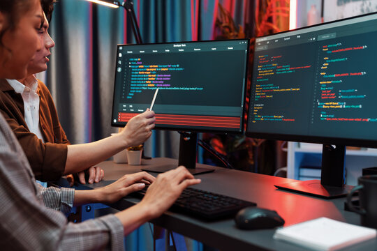 IT developers discussing with point to intelligent website development coder system running data online two screens information technology at neon light room at modern office. Infobahn.