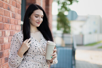 Stylish young woman enjoying a coffee moment against a red brick wall – lifestyle and fashion concept. 