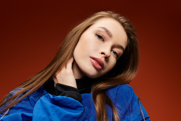 Fototapeta premium Vibrant woman showcases her stylish outfit while posing confidently against a bold backdrop.