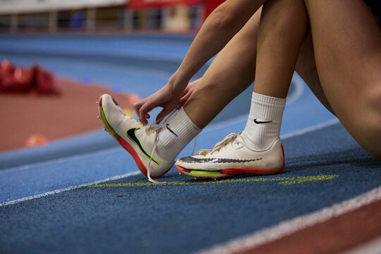 Runner tying sport shoes with grips for a sprint run during track and field competition. Kyiv - 12 January, 2024