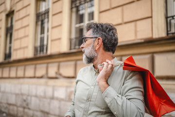 senior man hold shopping bags and looking for somebody on the street