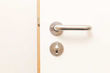 White wooden door with a metal handle. Locking mechanism and latch detail. Elegant interior design...
