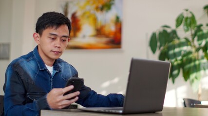 Fototapeta premium Business man using mobile smart phone and online working on laptop computer, surfing the internet, searching the information at office. male student online studying from home, e-learning