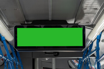 A large green digital display is mounted overhead in a public bus, ready to provide upcoming...