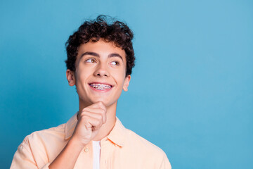 Charming young man in casual fashion poses against a blue background with a joyful smile and a thoughtful look