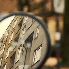 Urban scene with houses nd windows seen through a circular car mirror
