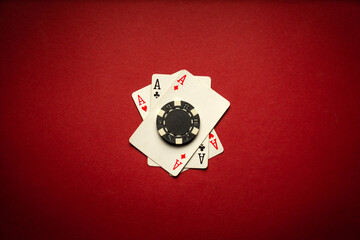 Three aces and a chip on a red table in a poker club. The concept of a successful game or a great...