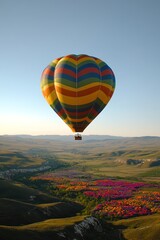 Fototapeta premium colorful hot air balloon floating over scenic valley filled with vibrant flowers golden light creates warmth and contrast