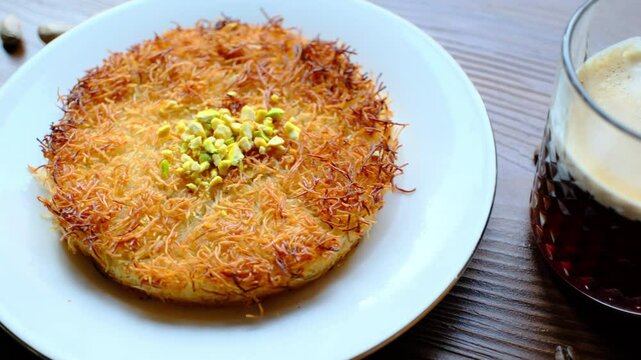 Close-up of local Turkish dessert kunefe with pistachios on a white plate	