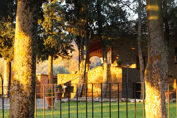 Obraz premium Trequanda, Italy - November 25, 2024: The territory of a charming historic building in Tuscany, originally a 13th-century medieval castle, now its a hotel. Features rustic stone walls, arched windows