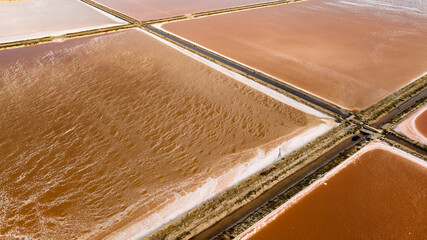 Aerial closeup of the tanks of a large salt mine. The water in the salt pan is red.