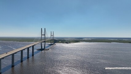 Obraz premium Suspension bridge with cars traveling over vast ocean coastal waterway with marsh wetlands in Brunswick, Georgia historic vacation destination Sydney Lanier Bridge 