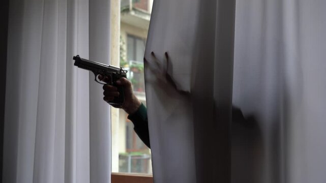 thief enters the apartment house from the window holding a revolver weapon gun. finding a thief in your home who endangers the safety of your family and sons. 
legitimate defense on private property