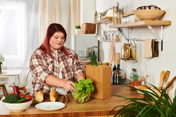 Bright afternoon finds a young plus size woman sorting fresh vegetables in her kitchen.