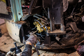 Fototapeta premium Repairman mechanic cleaning and oiling old and beat up engine of construction lift