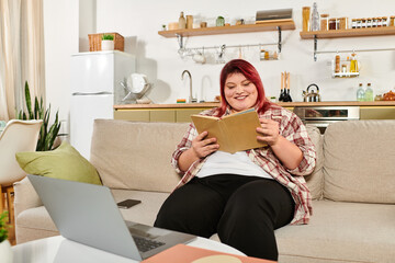 Beautiful plus size woman enjoying a book while relaxing on a comfortable couch at home.
