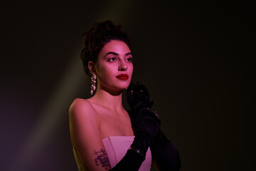 Fototapeta premium A stunning woman exudes elegance with stylish gloves and glamorous earrings in soft lighting.