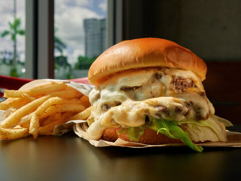 Doble Cheeseburger with lots of cheese on a table with fries