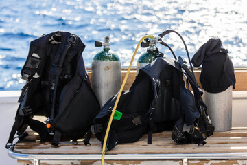 Concept of scuba diving with tank and equipment lying on a boat over blue sea and sunshine
