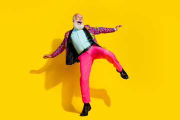 Fototapeta premium Full size photo of positive funny man enjoy dancing wear pink pants colorful blazer isolated on yellow background
