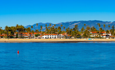 Waterfront panorama of Santa Barbara with Cabrillo Boulevard on the pacific coast of California (USA). Beach houses and tall palm trees in popular tourist destination seen from historic Stearns Wharf.