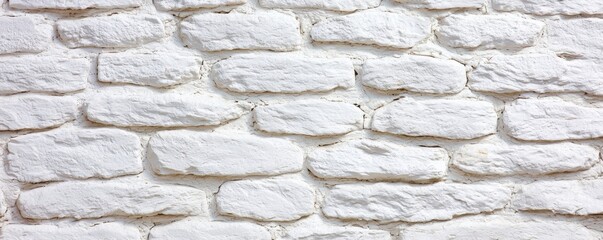 Fototapeta premium A textured, white stone wall with irregularly shaped bricks, offering a clean and minimalist aesthetic.