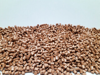 Milk chocolate color masterbatch granules on white background, color pigment carrier polymer in plastic industry. Suitable for plastic company catalog design