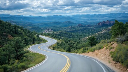 Fototapeta premium A winding road through a lush green valley, with mountains in the background.