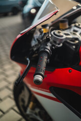 Close-Up Shot of a Motorcycle Handlebar with Detailed Grip Design and Vibrant Red Bodywork
