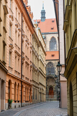 Obraz premium Beautiful alley in Prague's Jewish quarter with tall picturesque buildings and synagogue facade.