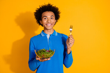 Photo of nice young man fork salad empty space wear blue shirt isolated on yellow color background