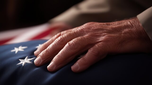 Elderly person's hand rests on folded American flag during tribute