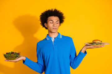 Photo of nice young man hold salad burger plates wear blue shirt isolated on yellow color background