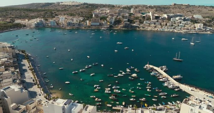 Aerial view of the marina in Bugibba, Malta. Tourism and travel port with yachts and boats embankment of a beautiful city with a landscape. High quality 4k footage