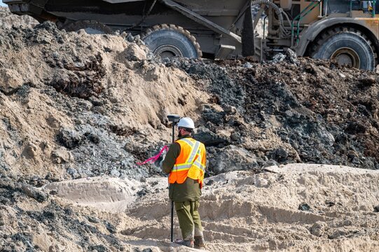 Surveyor carrying out a GPS survey on a construction site, with a dump truck in the background