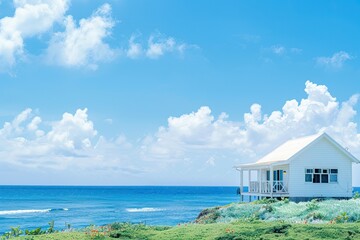Fototapeta premium Charming white oceanfront cottage, its bright exterior standing out against the blue of the sea and sky