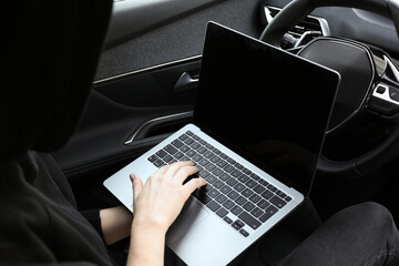 Thief hacking car system with laptop inside vehicle, closeup