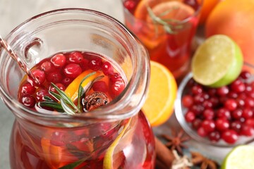 Tasty punch drink in glass jug and ingredients on table, closeup