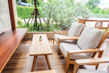 Fototapeta premium Wicker chair and wooden table in restaurant,Rattan chair in scandinavian interior of living room,Mediterranean minimal wall and green plant exterior architecturer,warm beige tones,copy space.