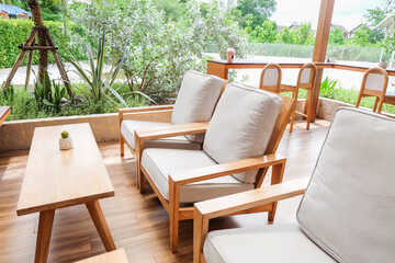 Fototapeta premium Wicker chair and wooden table in restaurant,Rattan chair in scandinavian interior of living room,Mediterranean minimal wall and green plant exterior architecturer,warm beige tones,copy space.