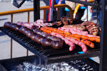 Variety of Sausages and Meats Grilling Over Charcoal at an Outdoor Barbecue Event