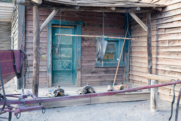 Rustic Wooden Cabin with Blue Accents and Traditional Horse Equipment, Exuding Historical Western Spirit
