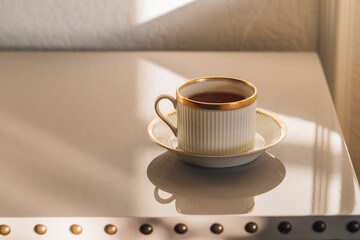 elegant white and gold cup and saucer of tea, coffee on gray lacquered table	